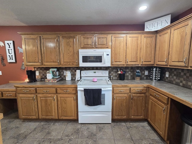 2373 W Rd, Mount Pleasant, AR 72561 - kitchen with white appliances, tile counters, tasteful backsplash, and brown cabinetry