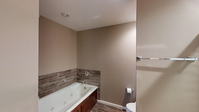full bath featuring a tub with jets, toilet, baseboards, and wood finished floors