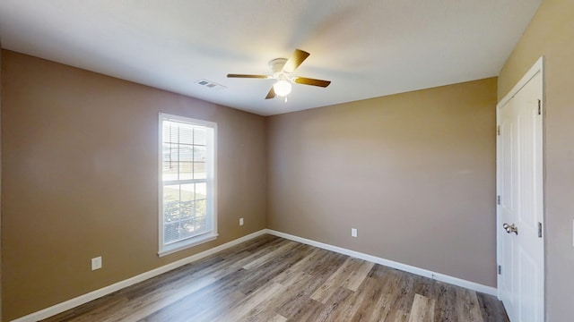 empty room with ceiling fan, light wood-style floors, and baseboards