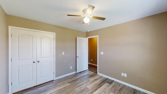 unfurnished bedroom with a closet, baseboards, light wood-style floors, and ceiling fan