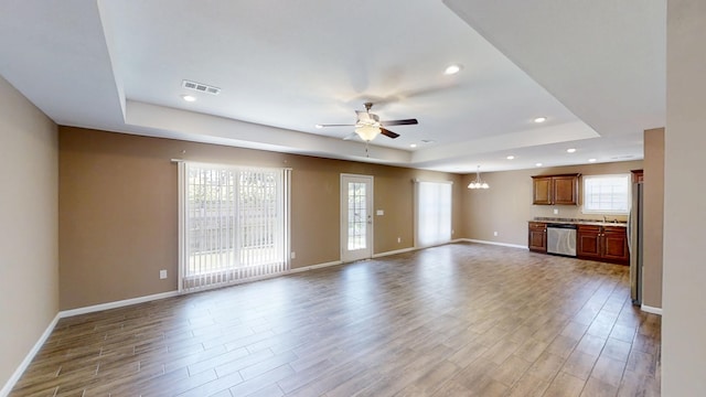 unfurnished living room with ceiling fan, a tray ceiling, wood finished floors, and recessed lighting