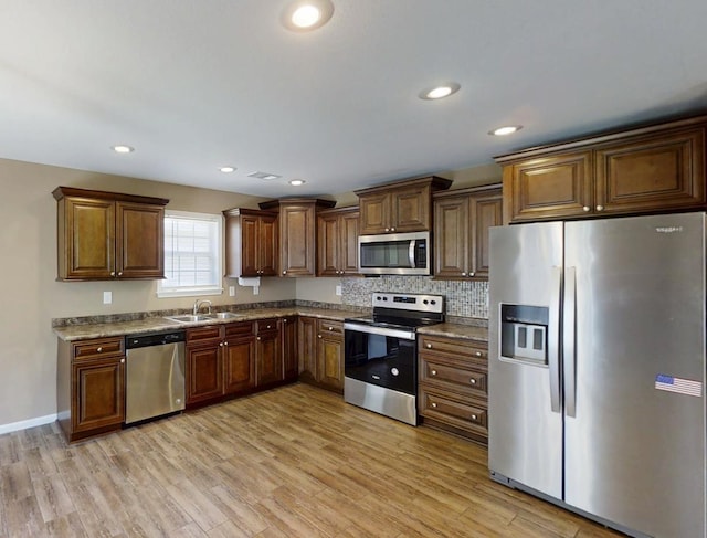 kitchen with stainless steel appliances, light wood-style flooring, tasteful backsplash, recessed lighting, and a sink