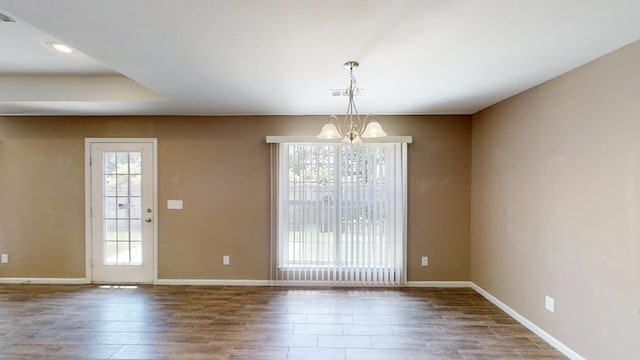 unfurnished dining area featuring a chandelier, baseboards, wood finished floors, and recessed lighting