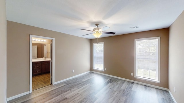 spare room featuring light wood-style floors, a ceiling fan, and baseboards