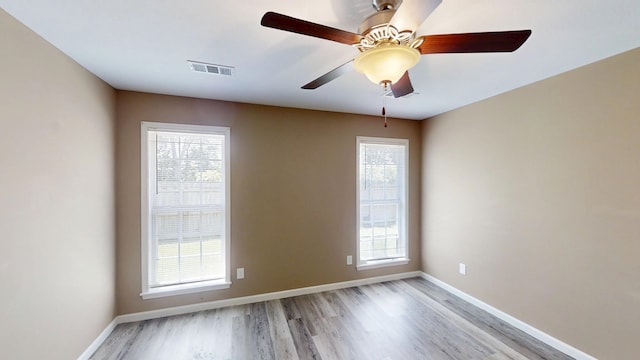 empty room with light wood finished floors, healthy amount of natural light, and baseboards