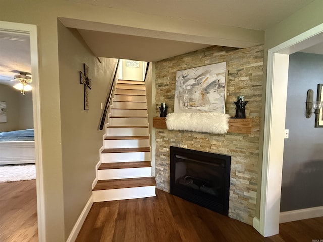 507 E Bruce St, Piggott, AR 72454 - stairs with a fireplace, wood finished floors, a ceiling fan, and baseboards