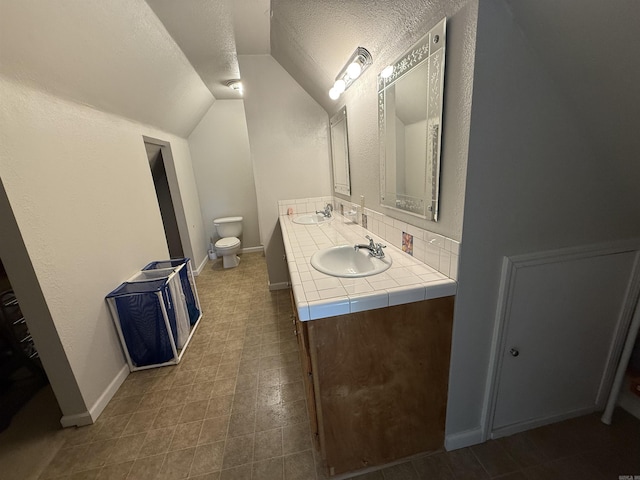 507 E Bruce St, Piggott, AR 72454 - full bath with vaulted ceiling, toilet, double vanity, a textured ceiling, and backsplash