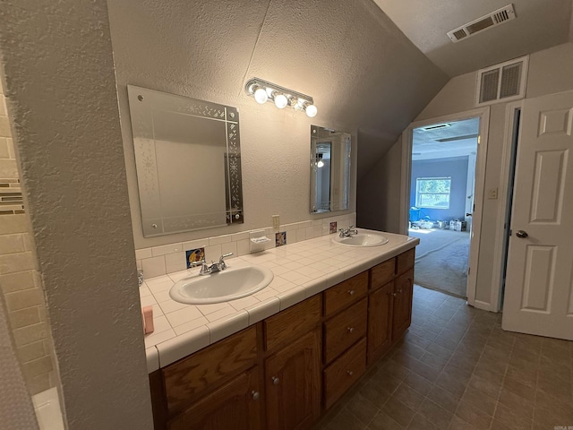 507 E Bruce St, Piggott, AR 72454 - bathroom with lofted ceiling, a textured wall, double vanity, and tile patterned floors