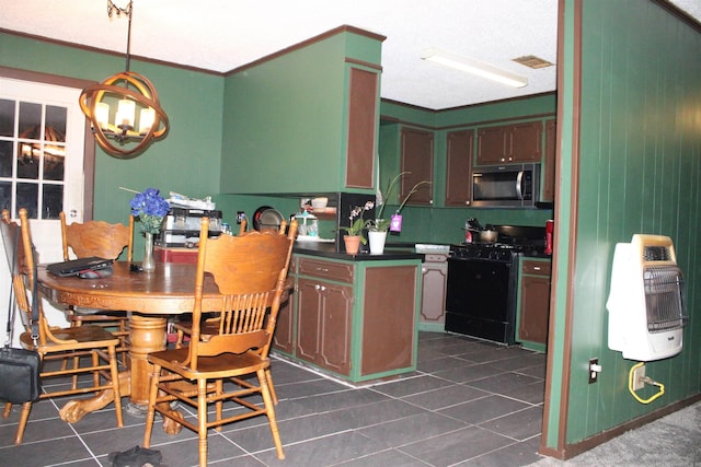 505 Woodland St, Malvern, AR 72104 - kitchen with black gas range oven, stainless steel microwave, dark tile patterned flooring, dark countertops, and a chandelier