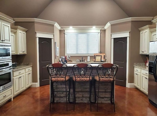 kitchen featuring cream cabinets, stainless steel appliances, crown molding, a breakfast bar area, and high vaulted ceiling