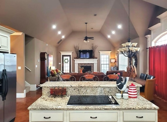 kitchen with stainless steel fridge with ice dispenser, black electric stovetop, open floor plan, a chandelier, and a ceiling fan