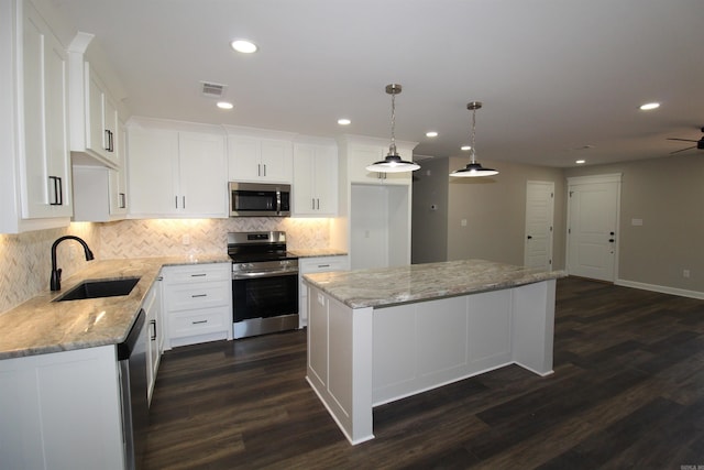 308 N Arch St, Sheridan, AR 72150 - kitchen featuring appliances with stainless steel finishes, a sink, dark wood-style flooring, backsplash, and a kitchen island