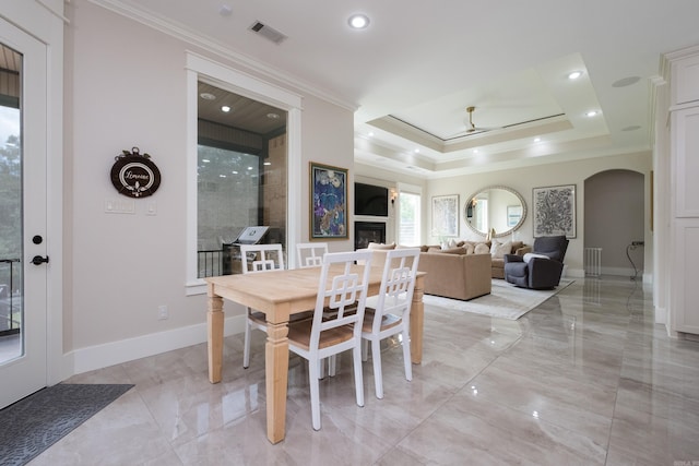 20 Accadia Ct, Little Rock, AR 72223 - dining space featuring ornamental molding, arched walkways, light marble finish flooring, a glass covered fireplace, and recessed lighting