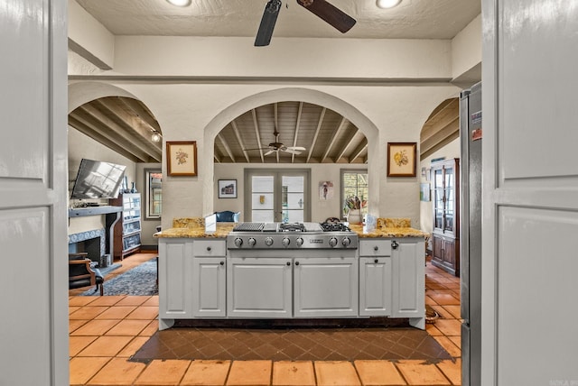 1729 N Spruce, Little Rock, AR 72207 - kitchen featuring ceiling fan, stainless steel gas cooktop, tile patterned flooring, white cabinetry, and a fireplace