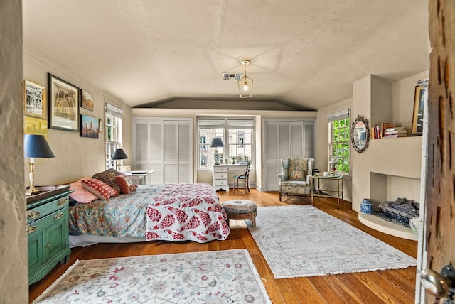 1729 N Spruce, Little Rock, AR 72207 - bedroom featuring vaulted ceiling, two closets, multiple windows, wood finished floors, and a textured ceiling