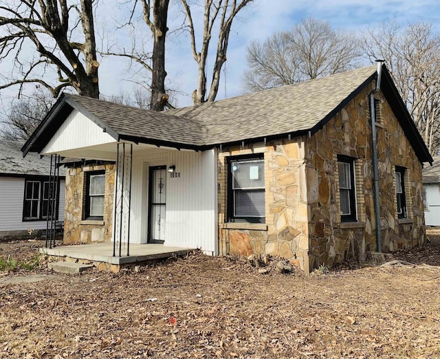 view of front of house featuring stone siding, a porch, and a shingled roof