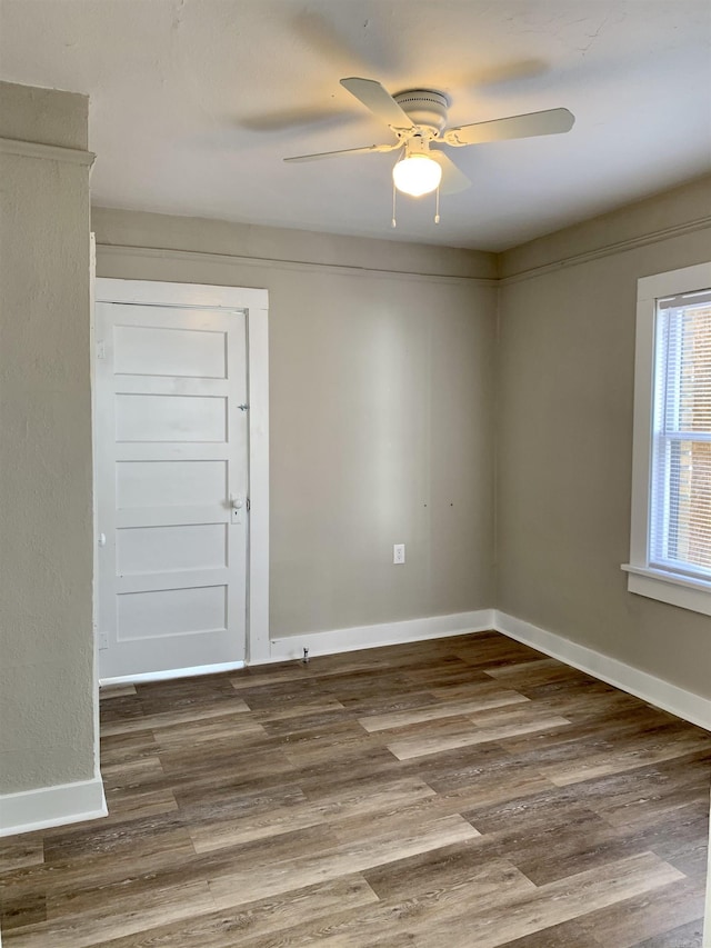 empty room with a ceiling fan, baseboards, and wood finished floors