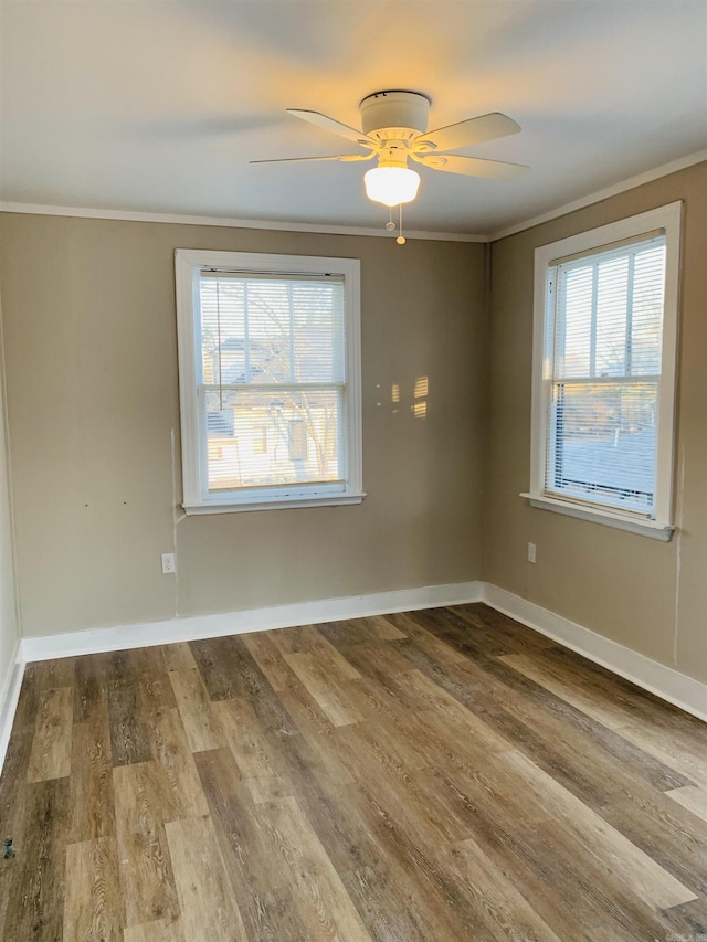 unfurnished room with ornamental molding, wood finished floors, a ceiling fan, and baseboards