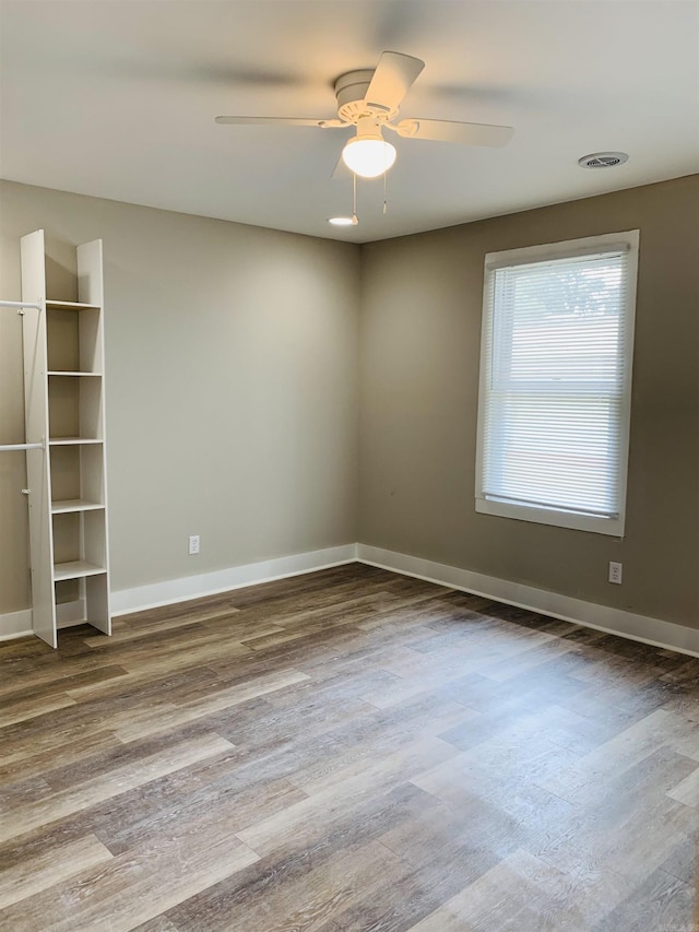spare room featuring wood finished floors, ceiling fan, and baseboards