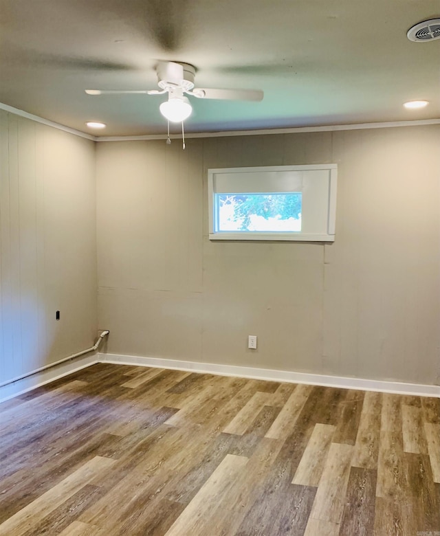 spare room featuring crown molding, wood finished floors, a ceiling fan, baseboards, and recessed lighting