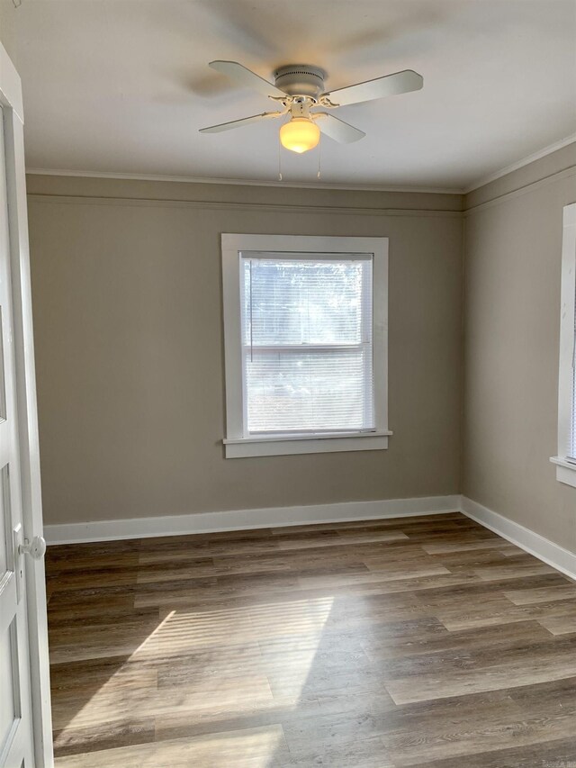 unfurnished room featuring wood finished floors, ceiling fan, baseboards, and crown molding