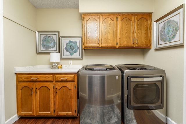washroom featuring cabinet space, washing machine and dryer, dark wood-type flooring, and baseboards