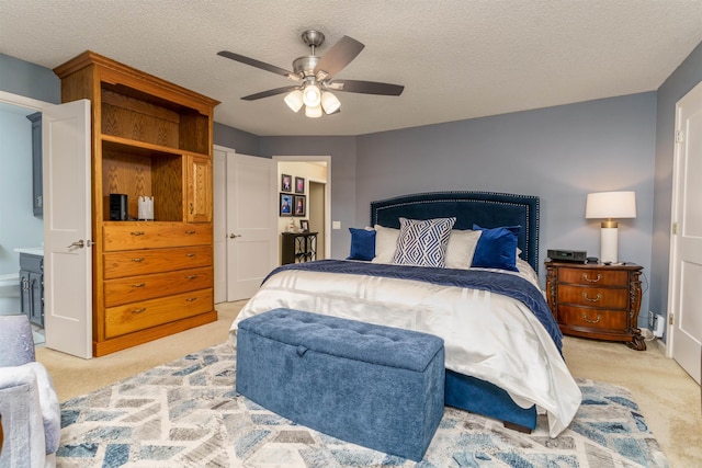 bedroom with light colored carpet, ceiling fan, and a textured ceiling