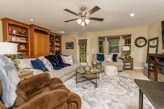 living room with ceiling fan, a textured ceiling, and baseboards