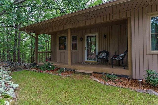 view of exterior entry featuring a porch and a yard