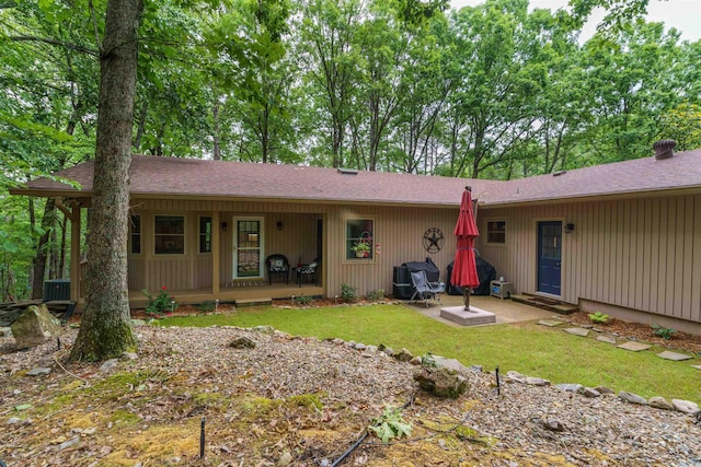 view of front facade with a front lawn, a porch, a shingled roof, and cooling unit