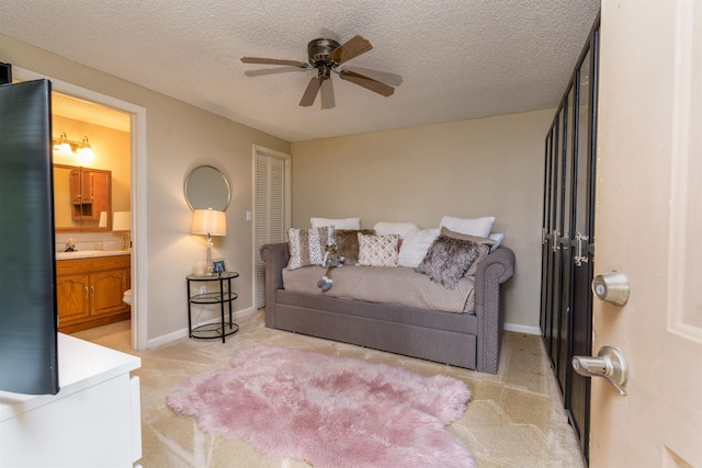 living area featuring a ceiling fan, light colored carpet, baseboards, and a textured ceiling