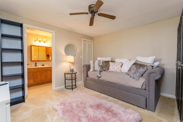 living area featuring light carpet, a ceiling fan, baseboards, and a textured ceiling