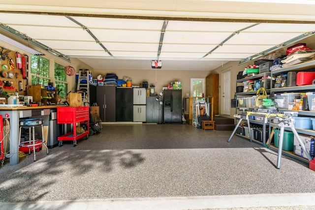 garage featuring black fridge with ice dispenser, a garage door opener, and a workshop area