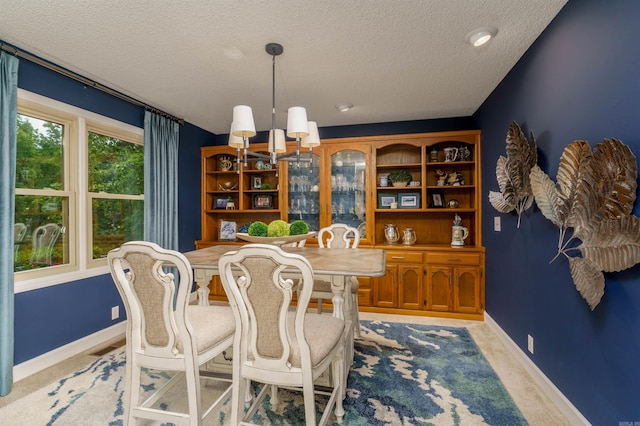 dining room with a textured ceiling, a chandelier, baseboards, and light carpet