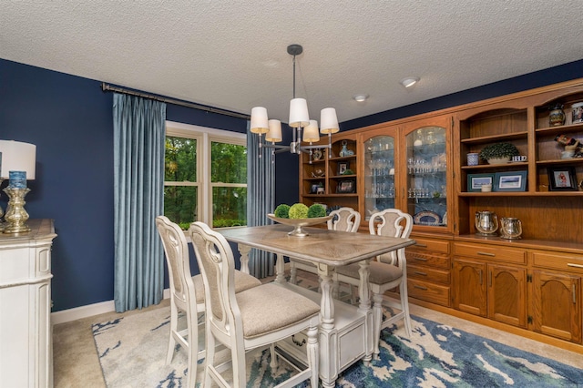 dining area featuring a textured ceiling, a chandelier, light colored carpet, and baseboards