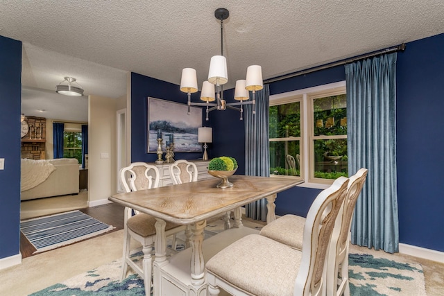 carpeted dining room featuring a chandelier, baseboards, and a textured ceiling