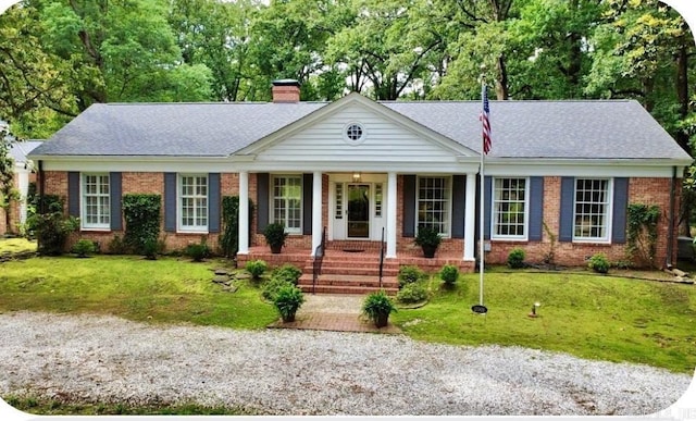 2001 W 46th Ave, Pine Bluff, AR 71601 - view of front facade with a chimney, brick siding, covered porch, a front yard, and a shingled roof