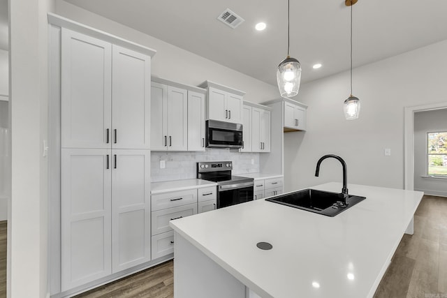 412 N 3rd St, Cabot, AR 72023 - kitchen with appliances with stainless steel finishes, a sink, wood finished floors, an island with sink, and tasteful backsplash