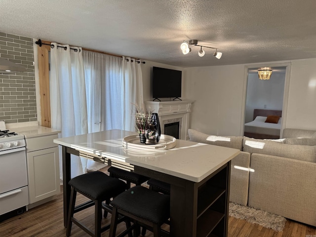 810 N Pear St, Searcy, AR 72143 - kitchen with white range with gas stovetop, open floor plan, a textured ceiling, a fireplace, and dark wood-style flooring