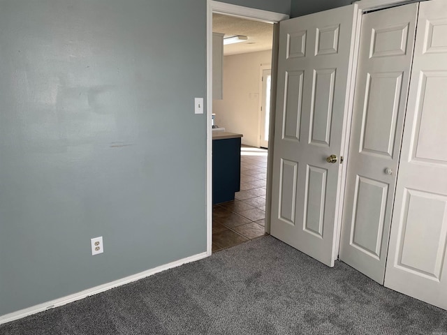 1117 Troy Dr, Benton, AR 72019 - unfurnished bedroom featuring a closet, dark carpet, and dark tile patterned floors