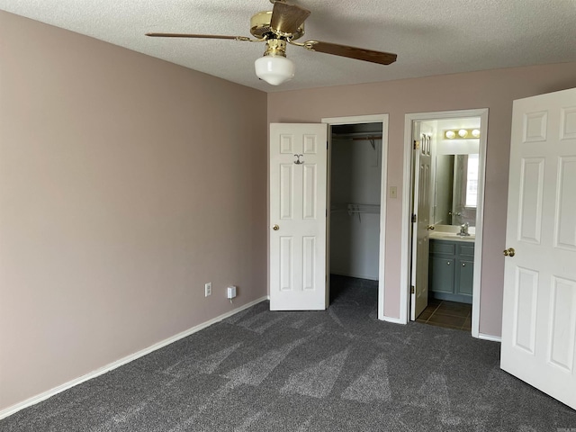 1117 Troy Dr, Benton, AR 72019 - unfurnished bedroom featuring dark colored carpet, a walk in closet, a textured ceiling, a closet, and ensuite bathroom