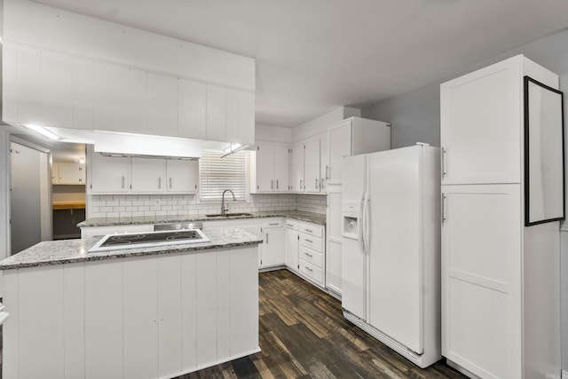 kitchen with white refrigerator with ice dispenser, a sink, tasteful backsplash, dark wood-style flooring, and white cabinetry