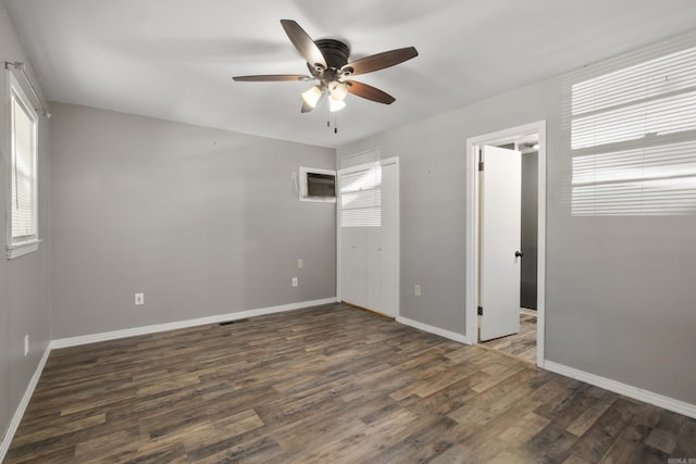 unfurnished bedroom featuring wood finished floors, baseboards, a ceiling fan, and a wall mounted AC