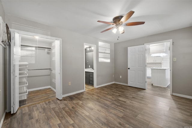 unfurnished bedroom featuring a walk in closet, a closet, and wood finished floors