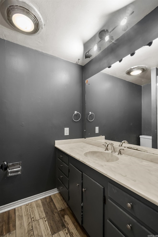 bathroom featuring vanity, wood finished floors, toilet, and baseboards