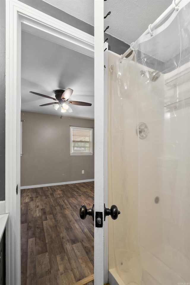 bathroom featuring a shower, wood finished floors, a ceiling fan, and baseboards
