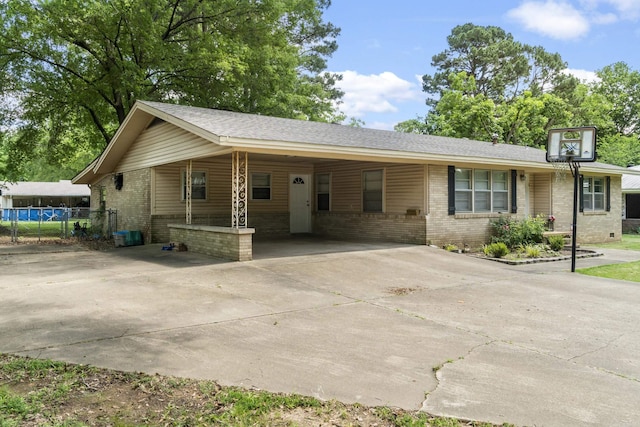 single story home featuring brick siding, concrete driveway, a carport, and roof with shingles