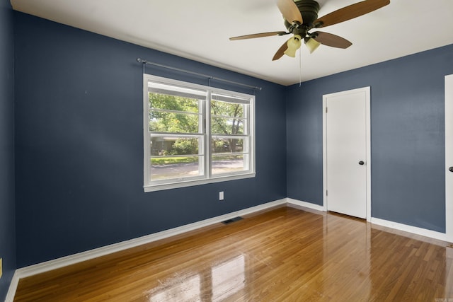 spare room featuring wood finished floors, baseboards, and ceiling fan