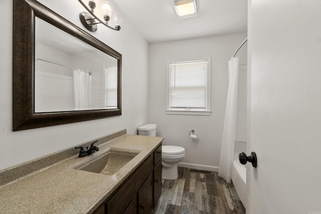 bathroom featuring vanity, wood finished floors, toilet, shower / tub combo, and baseboards