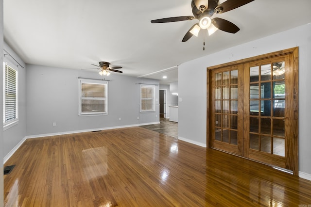 empty room featuring a ceiling fan, wood finished floors, healthy amount of natural light, and baseboards